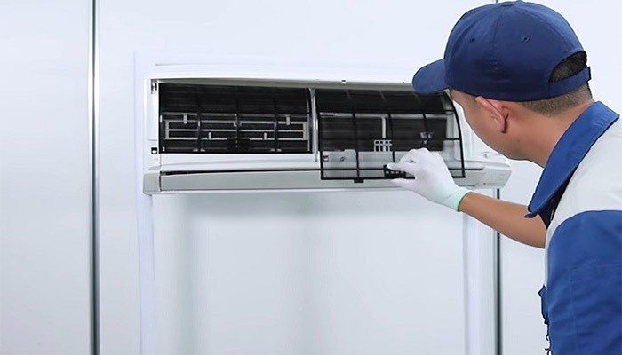 Hình ảnh một người thợ đang vệ sinh lưới lọc bụi của điều hòa
